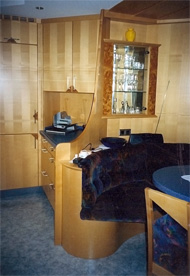 Wohnk&uuml;che; Ablagem&ouml;glichkeit neben verbauter K&uuml;hl-/Gefrierkombination, darunter Hochlade aus unbehandelten Massivholz f&uuml;r Brot und Geb&auml;ck